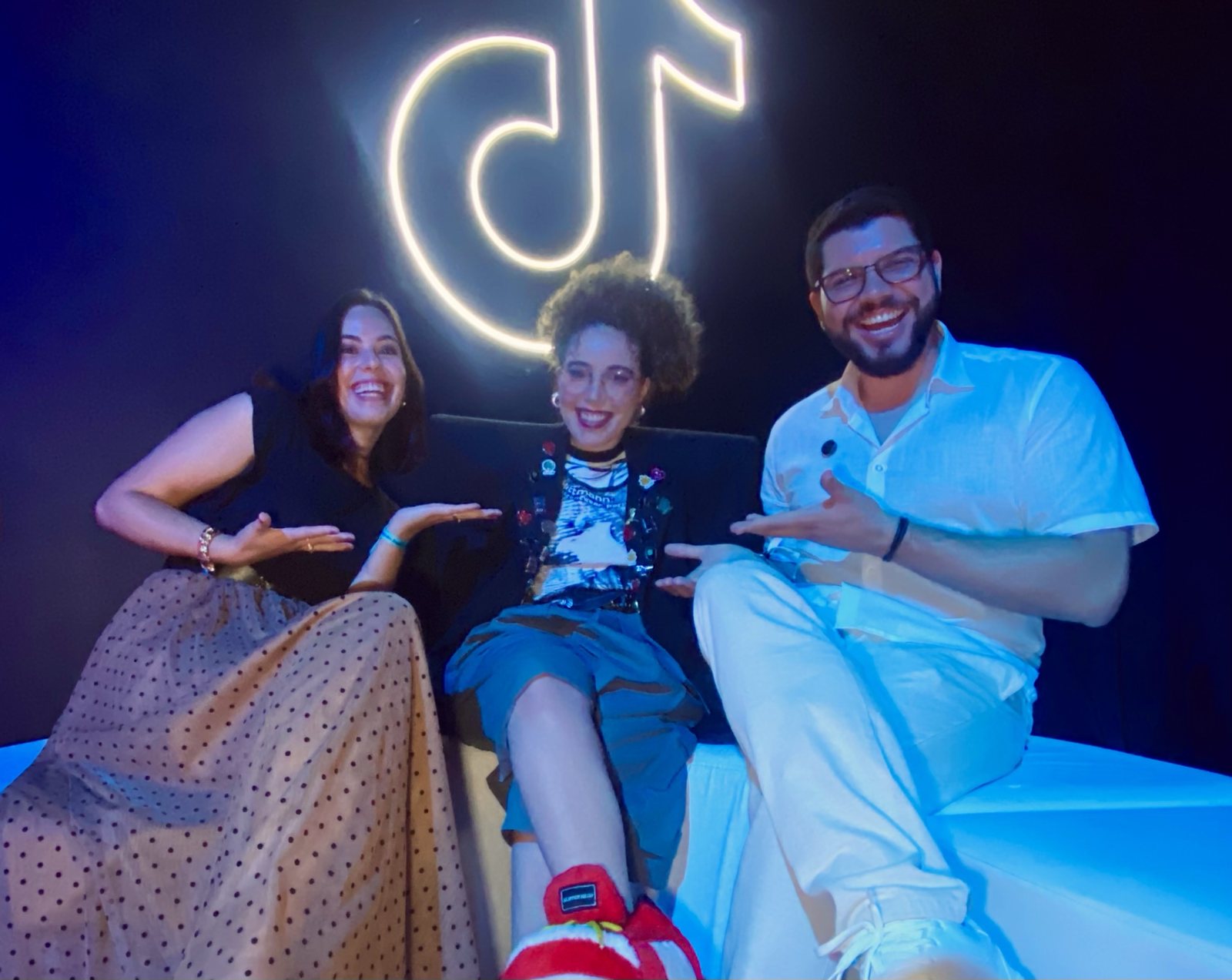 Amanda Rizzo, Gabi Marx e Felipe Ferreira sorrindo em frente ao logo do TikTok